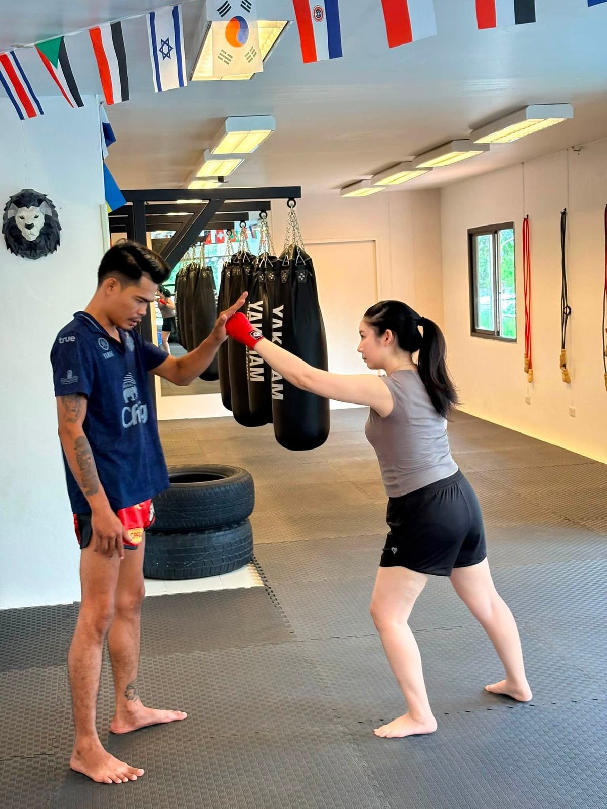Trainer holding pads for a beginner student at a Chiang Mai Muay Thai gym